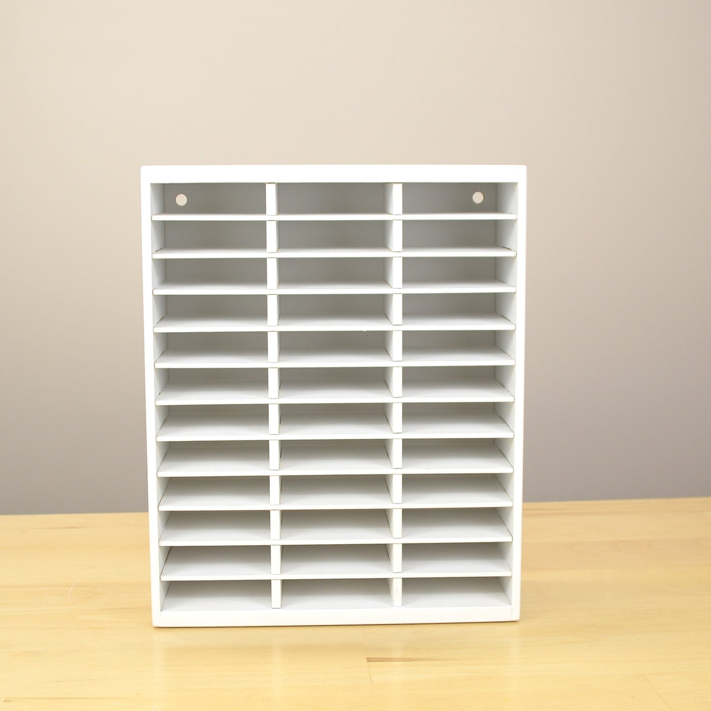 Empty ink pad organizer that's painted white, showing the back holes for wall mounting.