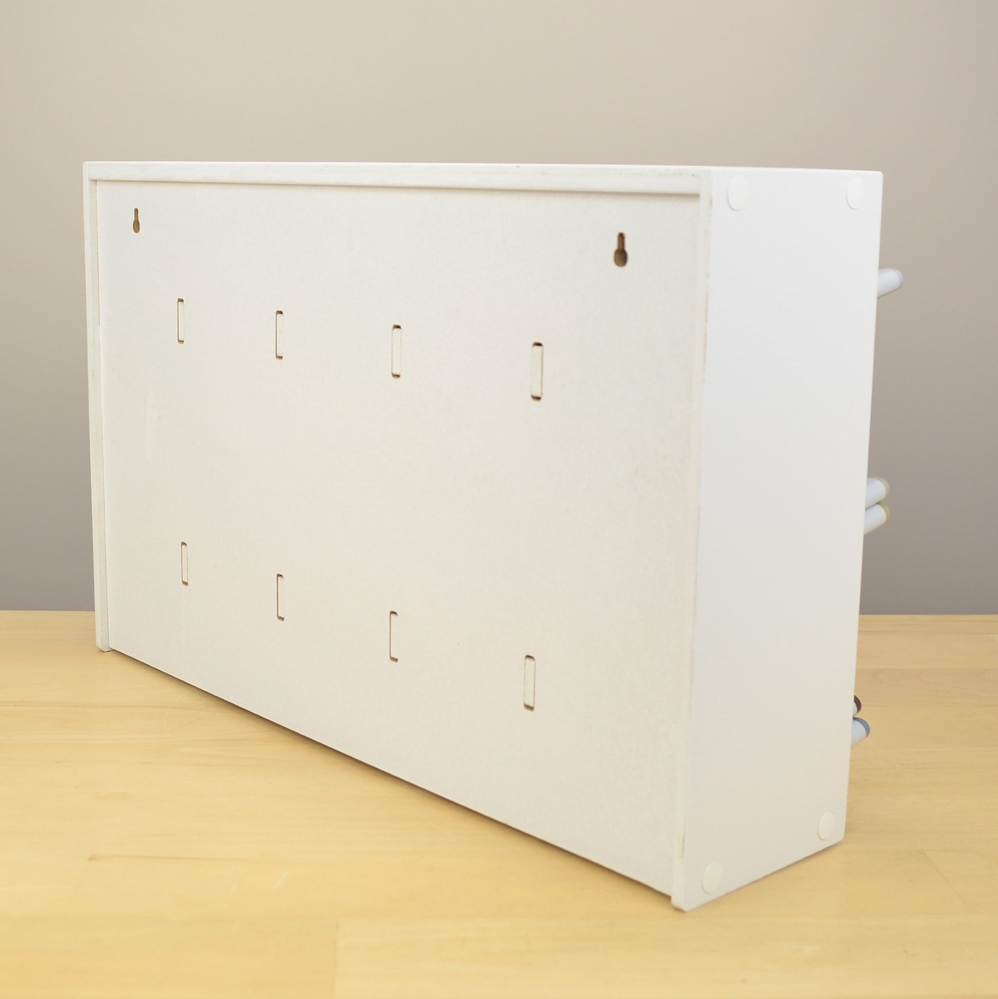 Back view of a white marker organizer showing the holes for wall mounting.