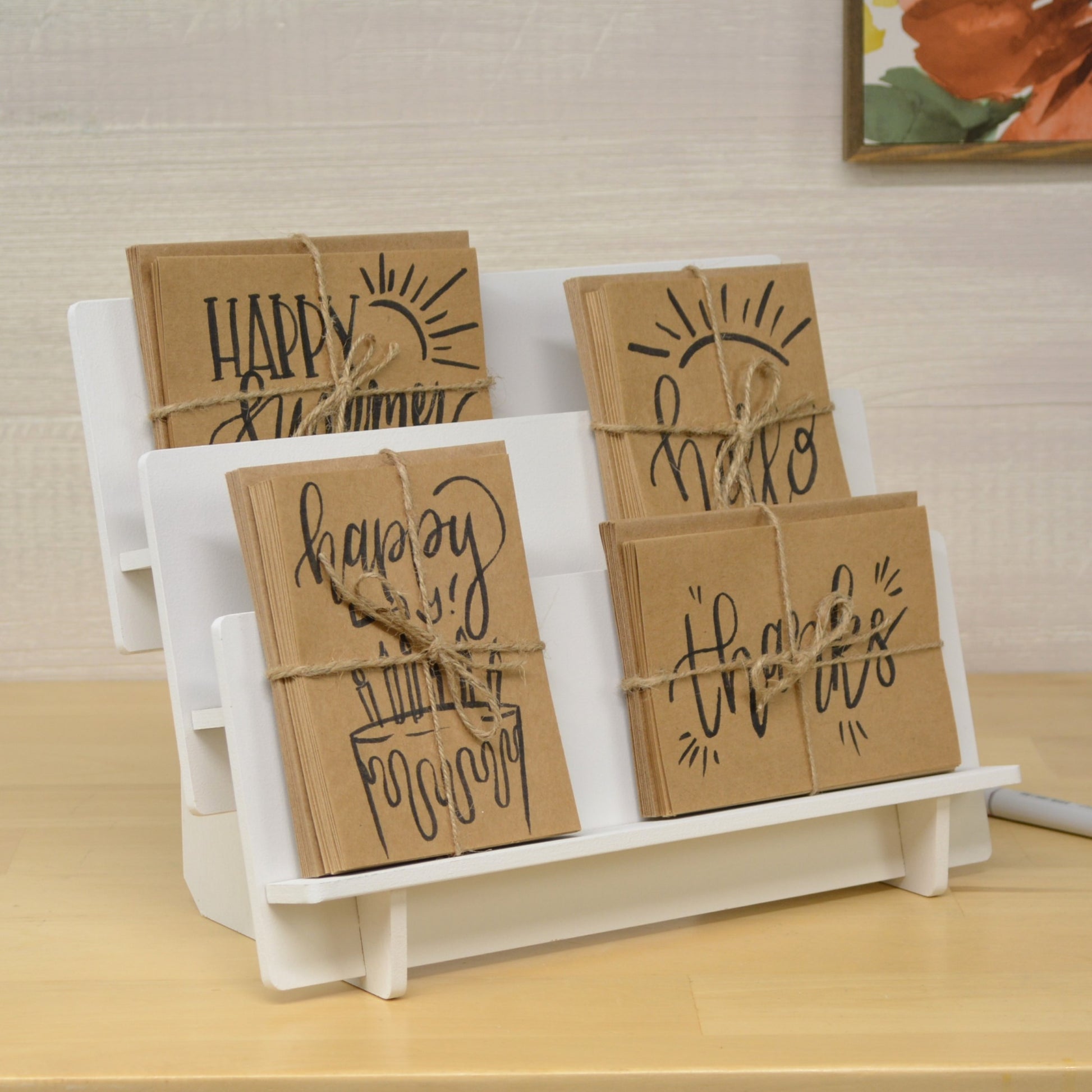 handmade greeting card bundles tied with jute twine and displayed in a tiered shelf on a tabletop