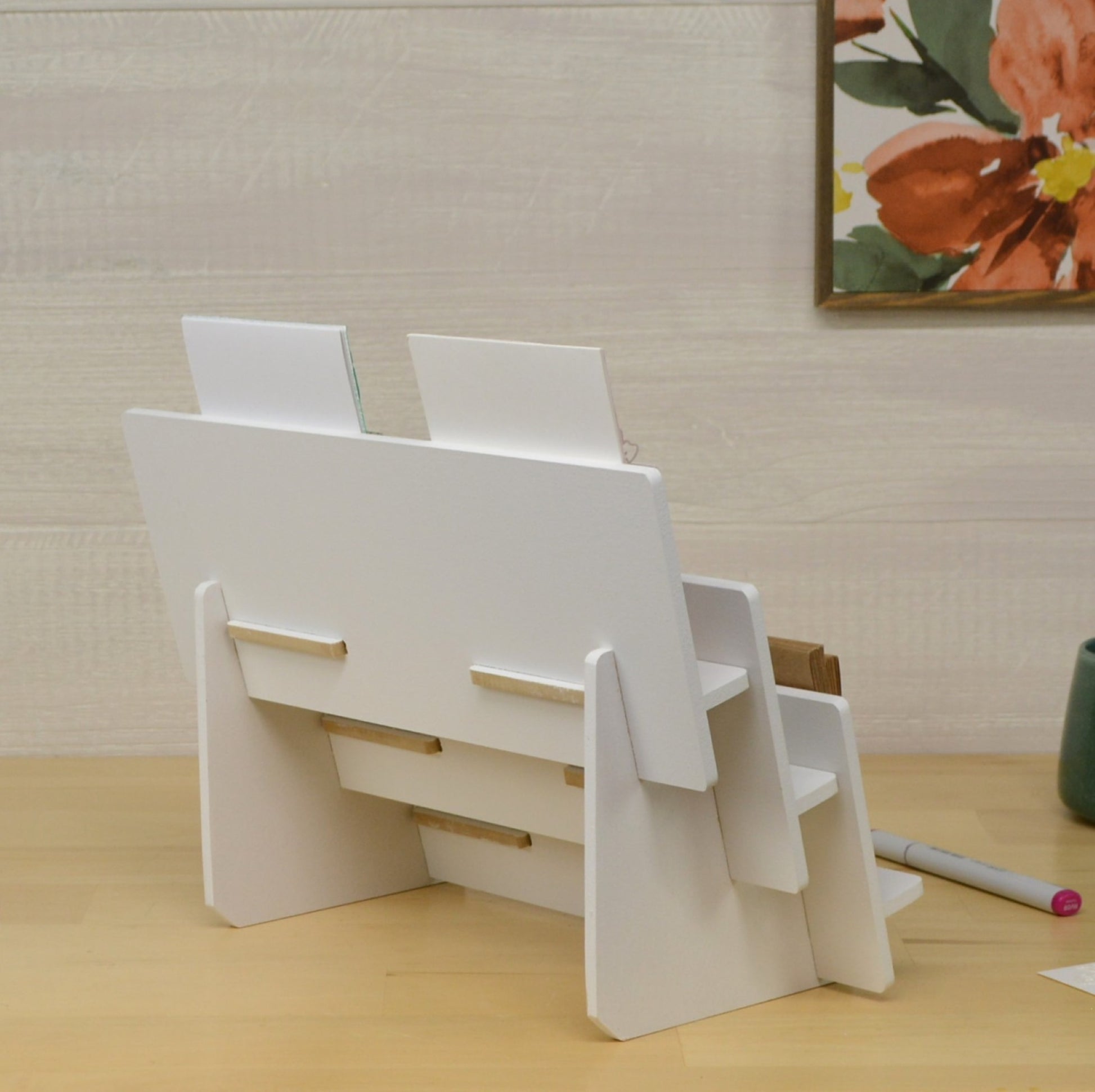back view of a white greeting card display stand that has three tiered shelves