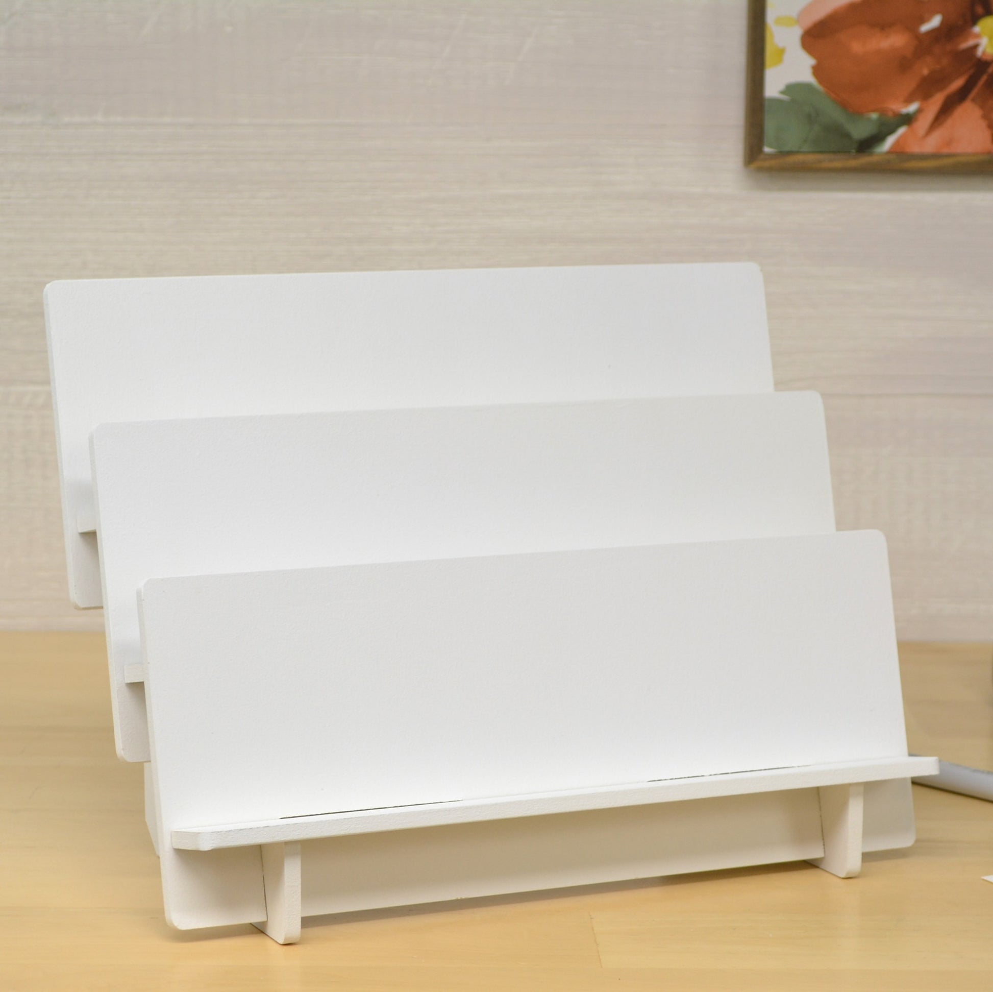 front view of an empty tiered shelf unit that's painted white and made to hold greeting cards