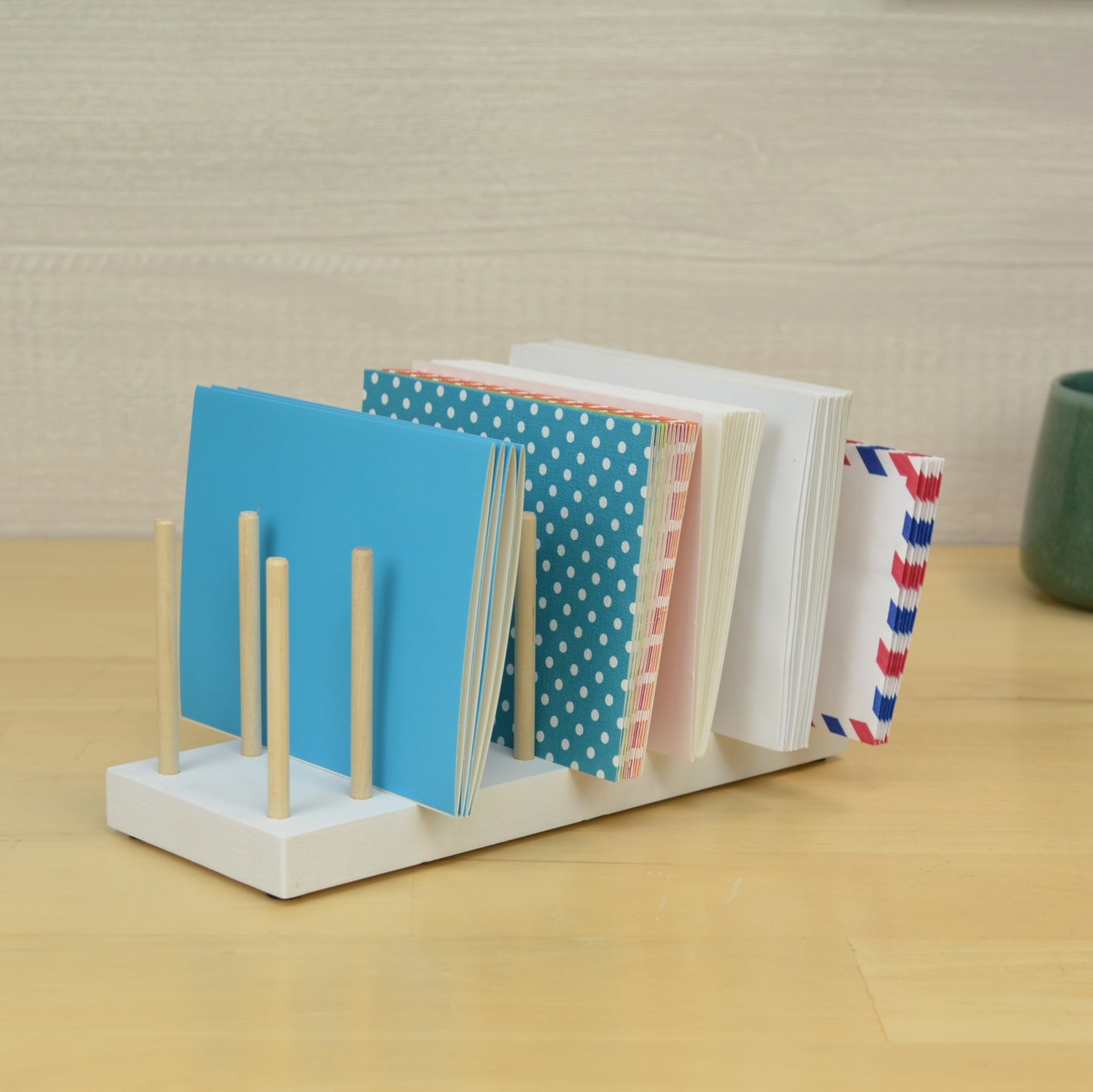 a white desktop organizer with wooden dowels to hold greeting cards and envelopes