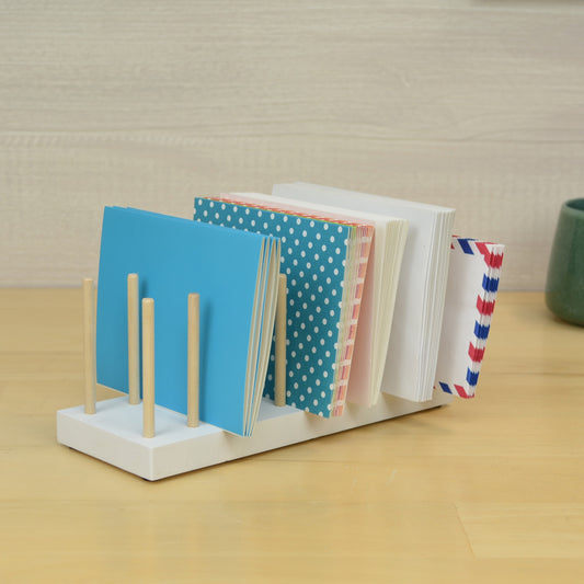 a white desktop organizer with wooden dowels to hold greeting cards and envelopes