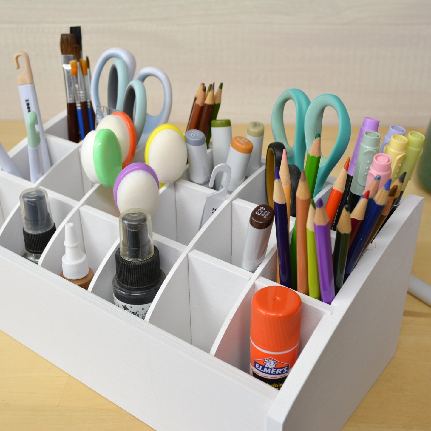 angle view of a white craft caddy showing eighteen sections holding pencils, markers, and scissors